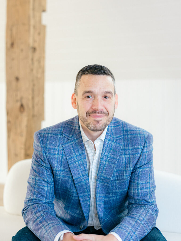 Danny wearing a blue suit sitting.